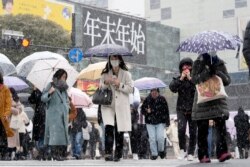 Orang-orang berjalan melintasi persimpangan Shibuya yang terkenal saat salju turun Kamis, 6 Januari 2022, di Tokyo. (Foto: AP)