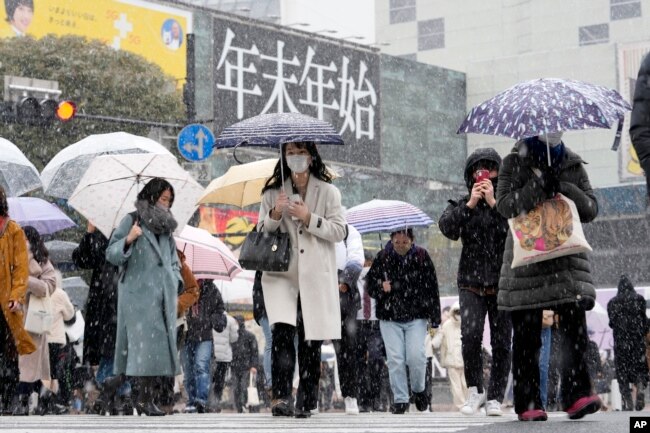Orang-orang berjalan melintasi persimpangan Shibuya yang terkenal saat salju turun Kamis, 6 Januari 2022, di Tokyo. (Foto: AP)