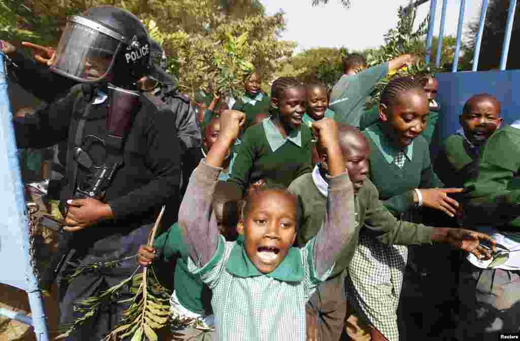 Students from Langata primary school run past riot police as they protest against a perimeter wall illegally erected by a private developer around their school playground in Kenya&#39;s capital Nairobi.