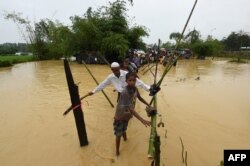 FILE - Rohingya refugees cross floodwaters at Thangkhali refugee camp in Bangladesh's Cox's Bazar district, Sept. 17, 2017.