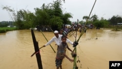 FILE - Rohingya refugees cross floodwaters at Thangkhali refugee camp in Bangladesh's Cox's Bazar district, Sept. 17, 2017.