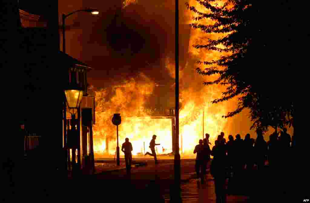 August 8: A shop is in flames as rioters gather in Croydon, south London.. Violence and looting spread across some of London's most impoverished neighborhoods, with youths setting fire to shops and vehicles, during a third day of rioting in the city that