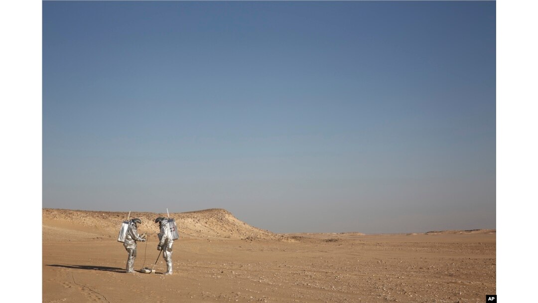 In this Feb. 7, 2018, photo, two scientists test space suits and a geo-radar for use in a future Mars mission in the Dhofar desert of southern Oman.