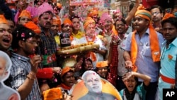 Bharatiya Janata Party supporters hold a shivling, a symbolic representation of Hindu god Shiva, and celebrate preliminary results showing a landslide BJP win in Varanasi, Uttar Pradesh, May 16, 2014.