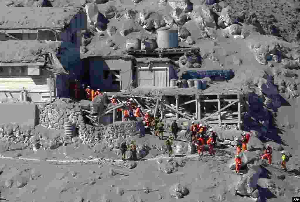 Rescue workers and Self-Defense Force soldiers search for missing climbers and survivors among ash covered mountain cottages on the top of Mount Ontake at Nagano prefecture.