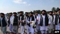 Juru bicara Taliban Zabihullah Mujahid (tengah, membawa selendang) didampingi oleh para pejabat untuk membrikan keterangan kepada media di bandara Kabul, 31 Agustus 2021. (WAKIL KOHSAR / AFP)