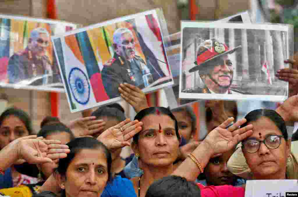 People holding posters of India's Chief of Defense Staff General Bipin Rawat salute to pay their respect to him after he and 12 others died in a helicopter crash, at a prayer ceremony in Ahmedabad.