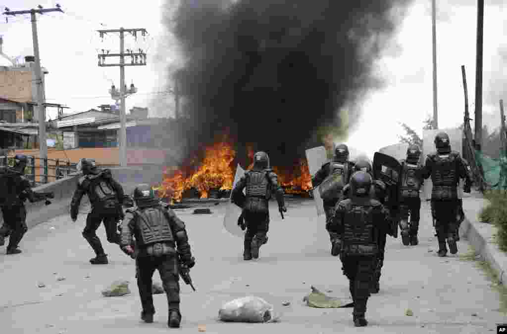 Police run toward a flaming barricade set by striking truckers in Bogota, Colombia, July 20, 2016. Hundreds of truckers - demanding a higher price for freight, lower fuel prices and fewer license regulations for cargo - clashed with police on the 41st day of their strike, which has made food scarce in some areas of the country.