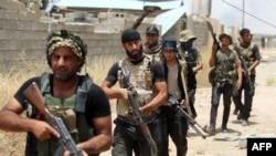 FILE - Fighters from the Popular Mobilization units deploy in the city of Baiji, north of Tikrit, as they fight alongside Iraqi forces against the Islamic State, June 9, 2015. 