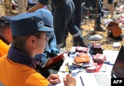Russian rescuer checking passports collected from the wreckage of a A321 Russian airliner in Wadi al-Zolomat, a mountainous area of Egypt's Sinai Peninsula. (Russian Emergency Ministry Handout photo)