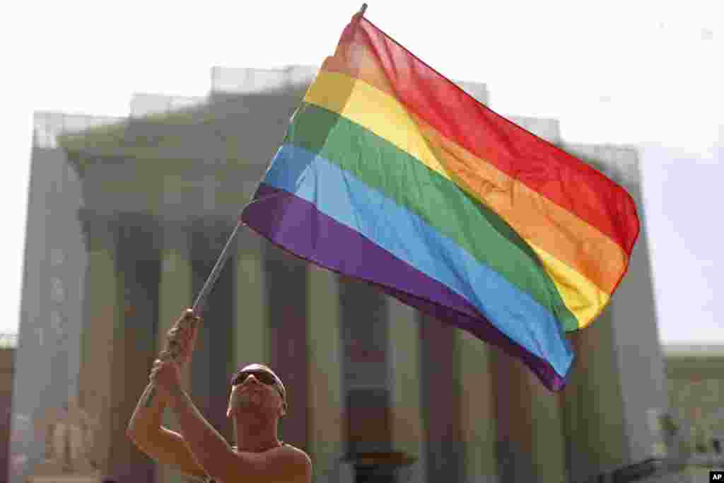 Vin Testa dari Washington melambaikan bendera pelangi tanda gerakan hak gay di depan Mahkamah Agung di Washington (24/6). (AP/Charles Dharapak)