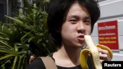 Amos Yee makan pisang saat tiba di pengadilan Singapura untuk konferensi pra-peradilan (17/4). (Reuters/Edgar Su)