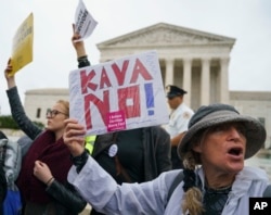 A protester with a sign that reads "KAVANO! I Believe Christine Blasey Ford" calls out in front of the Supreme Court on Capitol Hill in Washington, Sept. 24, 2018.