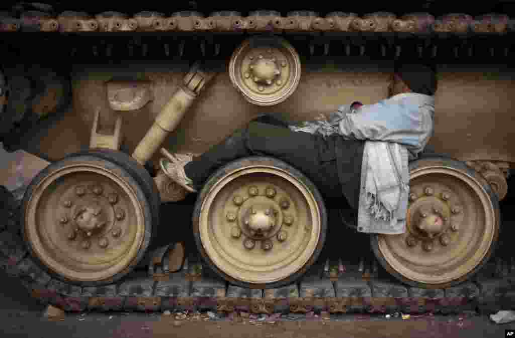 An Egyptian anti-Mubarak protesters sleeps on the wheels of a tank at Tahrir square, Feb. 6, 2011. 