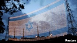 Bendera Israel berukuran 80 kali 60 meter digantung di atas jalan utama dari Tel Aviv ke Haifa pada 11 Mei 2005. (Foto: Reuters)