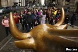 Tourists gather to photograph the Wall Street Bull in the New York Financial District, Jan. 12, 2017.