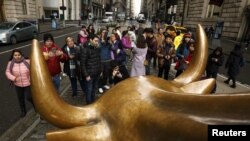 Tourists gather to photograph the Wall Street Bull in the New York Financial District, Jan. 12, 2017.