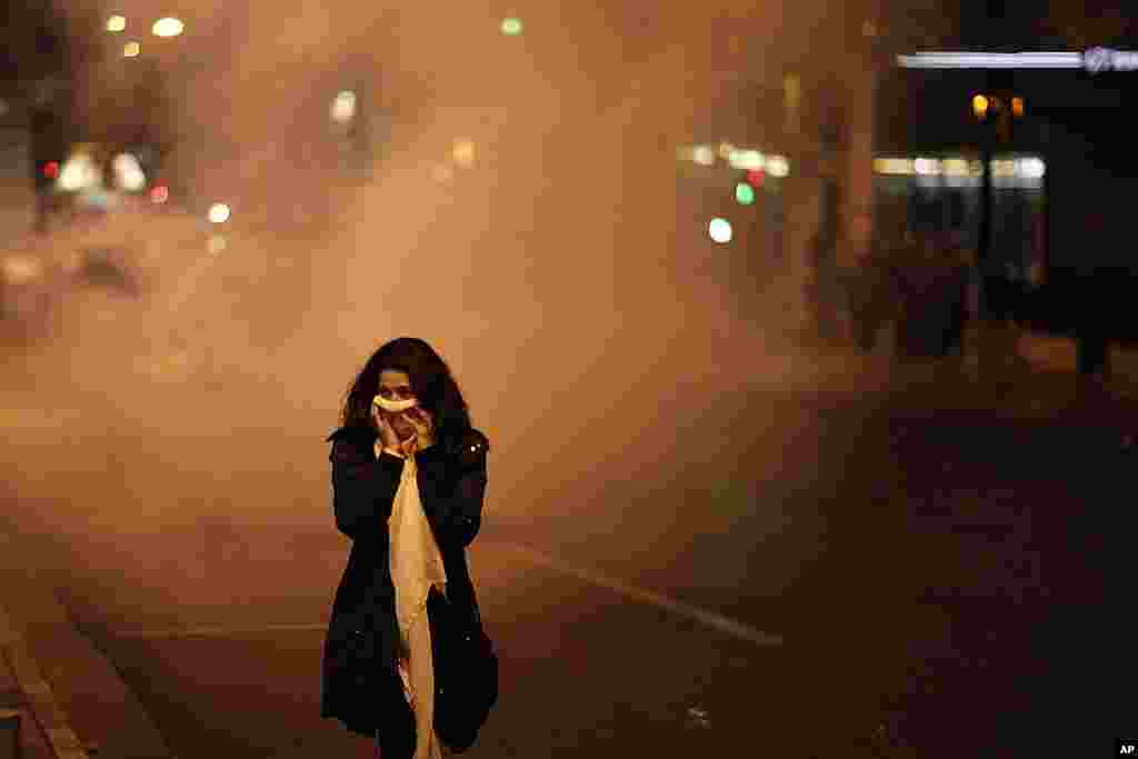 A pedestrian covers her face to protect from tear gas during a protest in front of the Greek parliament in Athens. (AP)