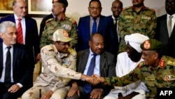 Utusan serikat pekerja Afrika untuk Sudan Mohamed al-Hacen Lebatt (kiri) duduk di sebelah wakil kepala dewan militer Sudan Jenderal Mohamed Hamdan Dagalo berjabat tangan dengan seorang jenderal militer setelah konferensi pers di Khartoum, 5 Juli 2019.