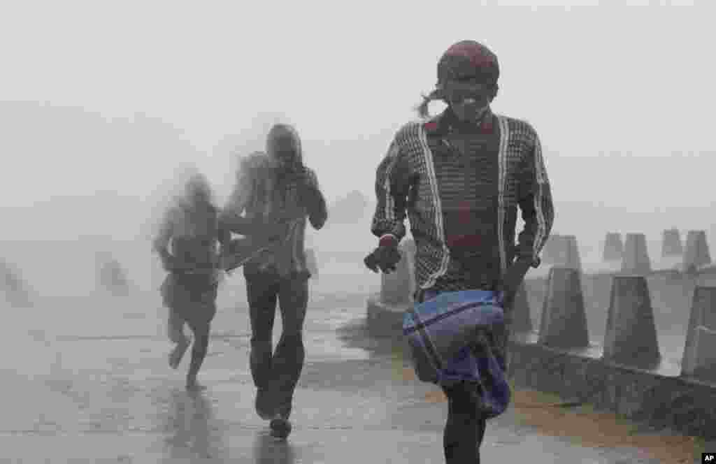 People run for shelter as heavy rain and wind gusts rip through the Bay of Bengal coast at Gopalpur, Orissa, Oct. 12, 2014.
