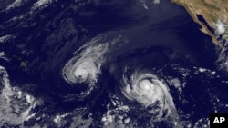 This image provided by NOAA Aug. 6, 2014 shows Hurricane Iselle, center, and tropical storm Julio, right. 