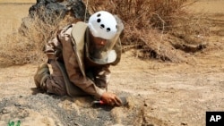 In this undated photograph released Aug. 19, 2018 by the state-run Emirates News Agency (WAM) on behalf of the Saudi-funded Masam anti-mine operation, an unidentified de-miner uncovers a mine near Marib, Yemen. 