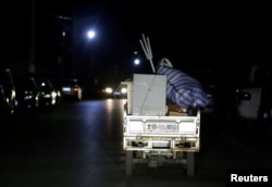 A migrant worker rides a tricycle filled with luggage as he was forced to move out of his apartment before midnight at a village outside the sixth ring road in Tongzhou district of Beijing, Nov. 23, 2017.