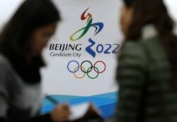 Para jurnalis mengobrol di dekat logo Olimpiade Musim Dingin 2022 di Markas Besar Olimpiade Beijing di Beijing, China, 4 November 2014.