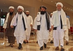 FILE - Taliban officials walk down a hotel lobby during talks in Doha, Qatar, Aug. 12, 2021.