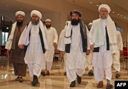 FILE - Taliban officials walk down a hotel lobby during talks in Doha, Qatar, Aug. 12, 2021.