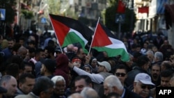 Warga Palestina mengibarkan bendera nasional saat mereka berbaris di jalan-jalan kota Ramallah di Tepi Barat yang diduduki, menyerukan penghentian perpecahan antara Fatah dan Hamas dan penyatuan Tepi Barat dan Jalur Gaza, pada 12 Januari 2019. (Foto: AFP )