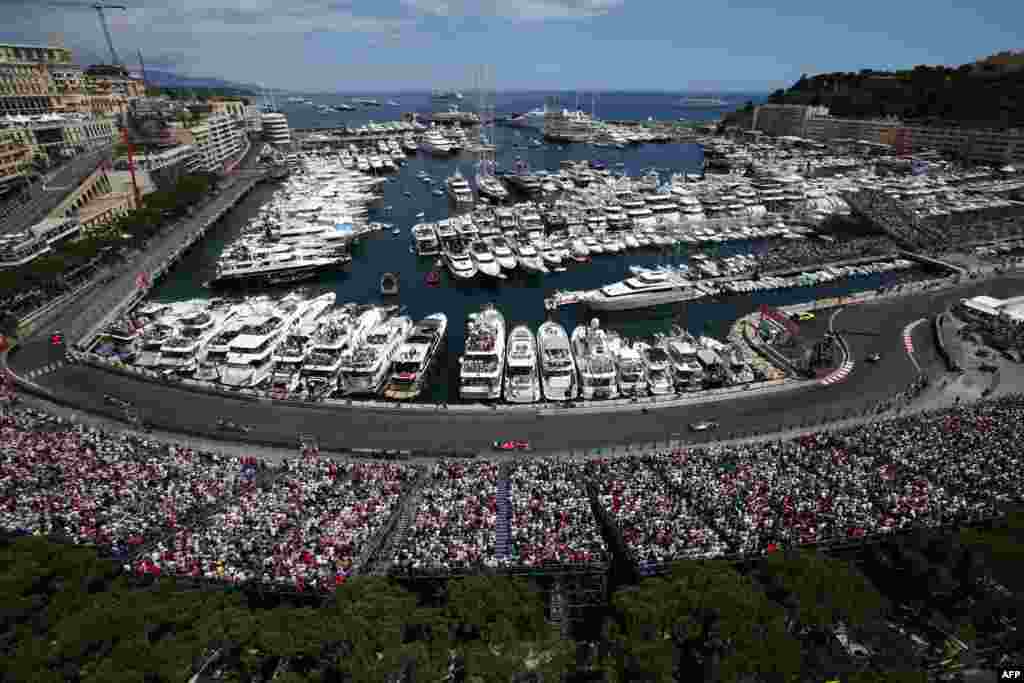 Spectators in terraces watch drivers racing along Monaco&#39;s harbor at the Monaco street circuit in Monte-Carlo during the Monaco Formula One Grand Prix.