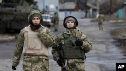 FILE: Ukrainian government army women soldiers patrol an area in the village of Debaltseve, Donetsk region, eastern Ukraine, Wednesday, Dec 24, 2014. 