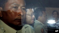 Ny Chakrya, second from left, former ADHOC and a National Election Committee member who worked at the organization, sits in a car and is transported back to an Anti-Corruption Unit, ACU, after a short appearance at Phnom Penh Municipal Court, in Phnom Penh, Cambodia, Saturday, April 30, 2016. Cambodian authorities arrested five human rights workers last Friday on accusations they tried to help cover up a woman's affair with the deputy leader of the opposition Cambodia National Rescue Party. The action is the latest in a series by Prime Minister Hun Sen's government putting legal pressure on its critics and political opponents. (AP Photo/Heng Sinith)