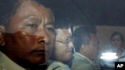 Ny Chakrya, second from left, former ADHOC and a National Election Committee member who worked at the organization, sits in a car and is transported back to an Anti-Corruption Unit, ACU, after a short appearance at Phnom Penh Municipal Court, in Phnom Penh, Cambodia.