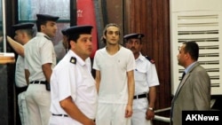 FILE - Egyptian photojournalist Mahmoud Abu Zied, known by his nickname Shawkan, center, appears before a judge for the first time after spending more than 600 days in prison in Cairo for covering deadly police crackdown on protests, May 14, 2015. 