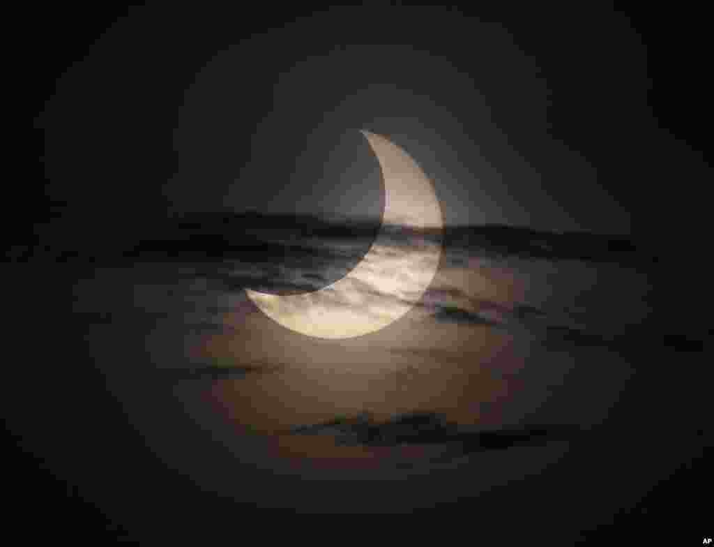 An annular solar eclipse is partially seen at sunrise, May 21, 2012, from the coastal township of Gumaca, Quezon province, southeast of Manila, Philippines.