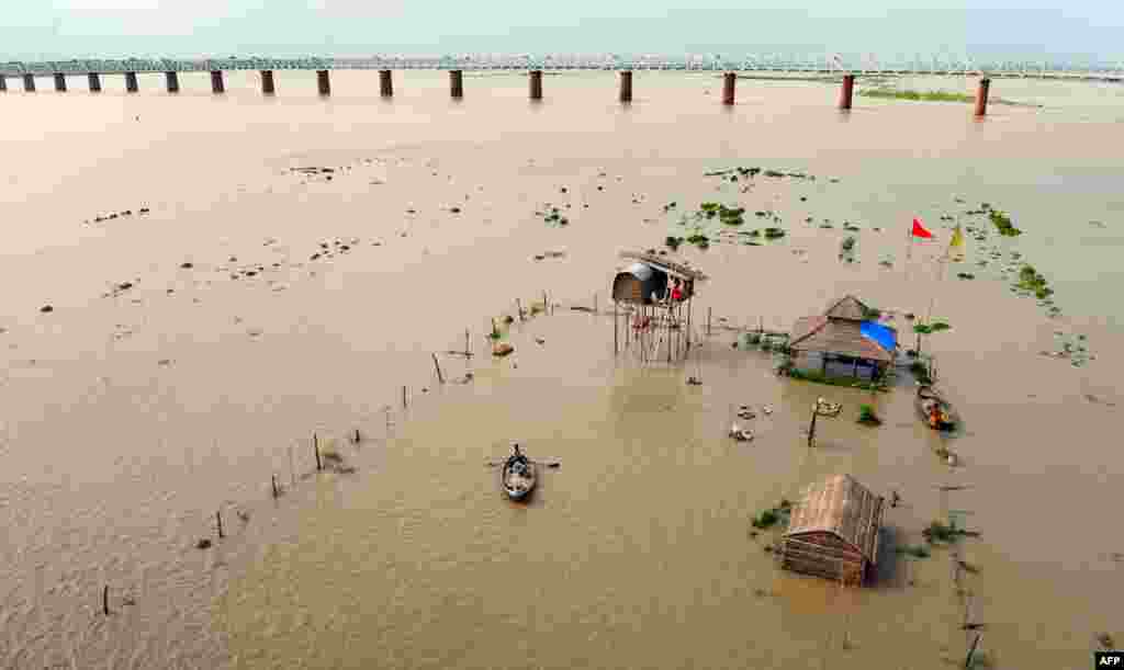 An Indian boatman rows passengers from submerged huts of 'sadhus' - holy men - on the flooded banks of the Ganga river after water levels rose, in Allahabad. Heavy rain in several areas of north India has caused rivers to reach dangerous levels and flooding has occured in various places.