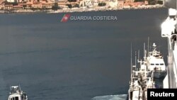 Para migran dipindahkan dari kapal milik LSM Aita Maria ke kapal Italia, Rubattino di lepas pantai Palermo, Italia, Minggu, 19 April 2020. Mereka dipindahkan untuk dikarantina karena wabah virus corona (Covid-19).