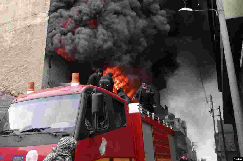 Firefighters attempt to extinguish a fire at a factory that activists say was shelled by forces loyal to Syria&#39;s President Bashar al-Assad at al-Haidariah area in Aleppo. 