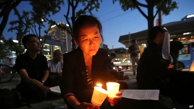 FILE - A woman lights candles during a service for peace on the Korean Peninsula near the U.S. Embassy in Seoul, South Korea, Aug. 31, 2017.