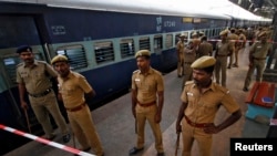 Indian policemen stand guard next to a passenger train in which two explosions occurred, at the railway station in the southern Indian city of Chennai, May 1, 2014.