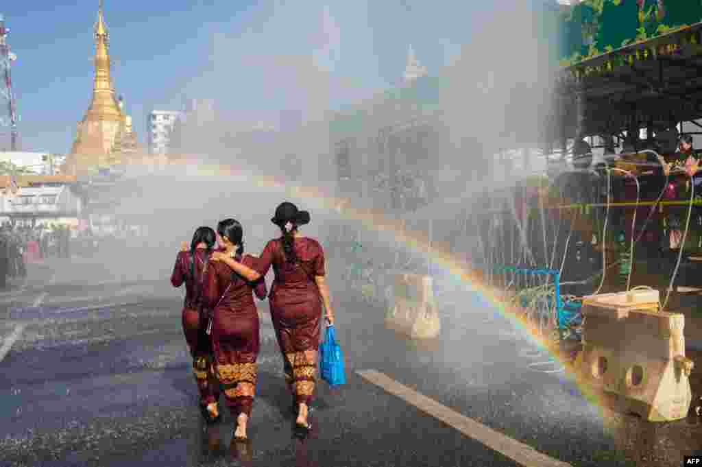 عکسی از زنان میانماری با زمینه یک رنگین کمان در حاشیه یک مراسم بودایی