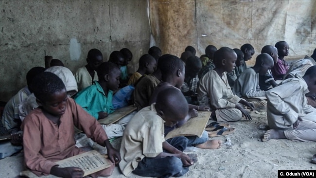 Almajirai in Maiduguri read scriptures from the Quran on wooden slates.