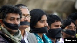 FILE - Activists of the leftist alliance cover their mouths with black cloths as they join in a rally to demand a new election under caretaker government, in Dhaka, Bangladesh, Jan. 3, 2019.
