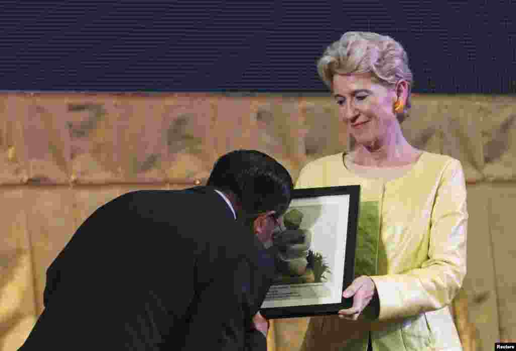 Cambodia&#39;s Prime Minister Hun Sen kisses a portrait of one of the two 10th-century stone statues, which were returned to Cambodia from New York&#39;s Metropolitan Museum of Arts, during the opening ceremony of the 37th session of the World Heritage Committee at the Council of Ministers in Phnom Penh.