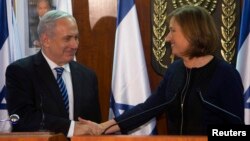 Israel's Prime Minister Benjamin Netanyahu (L) shakes hands with former Foreign Minister Tzipi Livni, head of the centrist Hatenuah party, during their joint statement at the Knesset, the Israeli parliament, in Jerusalem, February 19, 2013.