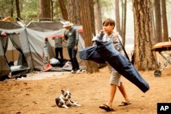 River Martinez, 10, breaks camp at the Upper Pines Campground in Yosemite National Park, Calif., July 25, 2018. Martinez's family, visiting from Los Angeles, had to cut their stay short as portions of Yosemite closed to allow crews to battle the Ferguson Fire burning nearby.