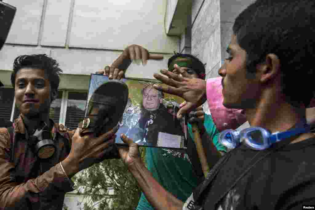 Supporters of Tahir ul-Qadri use a sandal to hit a portrait of Prime Minister Nawaz Sharif as a sign of disrespect after storming the building of the state television channel PTV in Islamabad, Sept. 1, 2014.