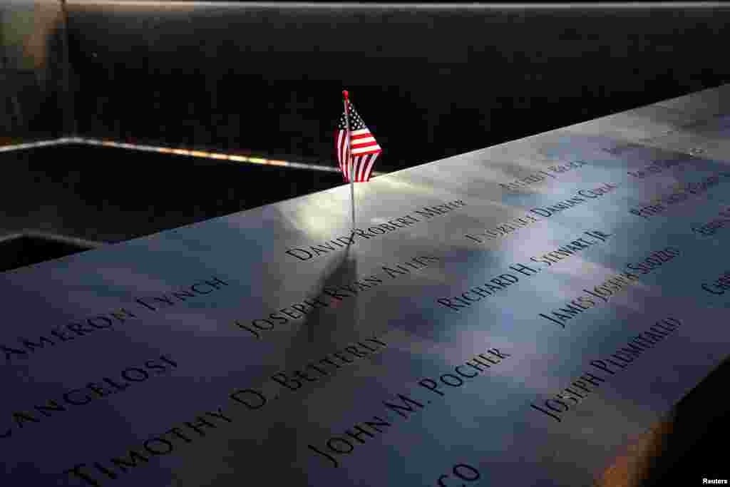 An American flag is seen left in the egraved names of 9/11 victims at the edge of the north reflecting pool at the 9/11 Memorial in lower Manhattan in New York, during ceremonies commemorating the 18th anniversary of terrorist attacks.